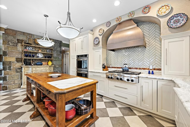 kitchen with appliances with stainless steel finishes, decorative light fixtures, custom range hood, decorative backsplash, and light tile patterned floors