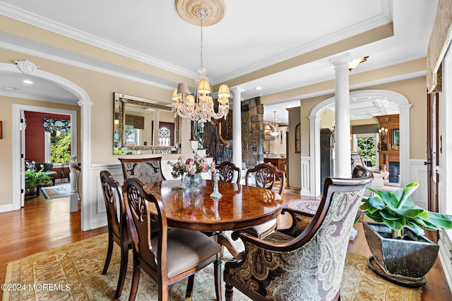 dining room with hardwood / wood-style flooring, crown molding, a healthy amount of sunlight, and ornate columns