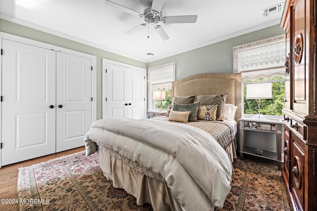 bedroom with ceiling fan, multiple windows, dark hardwood / wood-style flooring, and ornamental molding