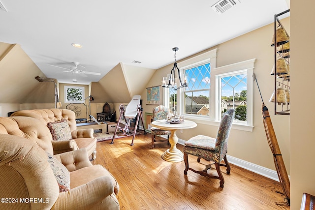 living room with light wood-type flooring, ceiling fan with notable chandelier, and vaulted ceiling