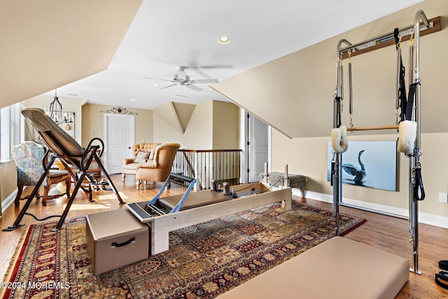 exercise room with ceiling fan, vaulted ceiling, light hardwood / wood-style floors, and a barn door