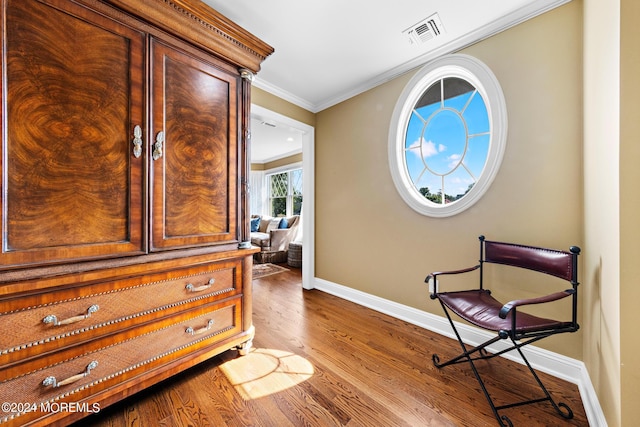 living area with hardwood / wood-style floors and ornamental molding