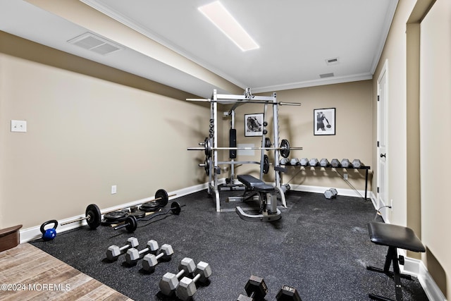 exercise room with crown molding and hardwood / wood-style flooring