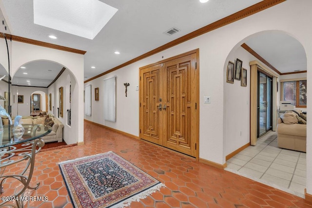 entryway with crown molding, visible vents, baseboards, recessed lighting, and arched walkways