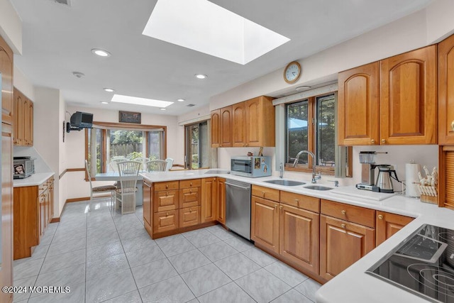 kitchen featuring plenty of natural light, a sink, appliances with stainless steel finishes, and a peninsula
