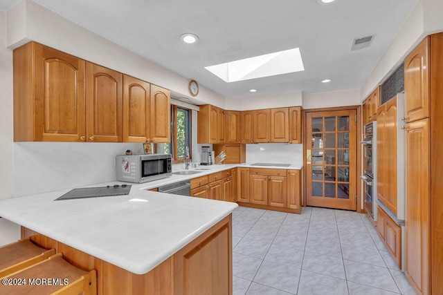 kitchen featuring visible vents, a peninsula, light countertops, appliances with stainless steel finishes, and a skylight
