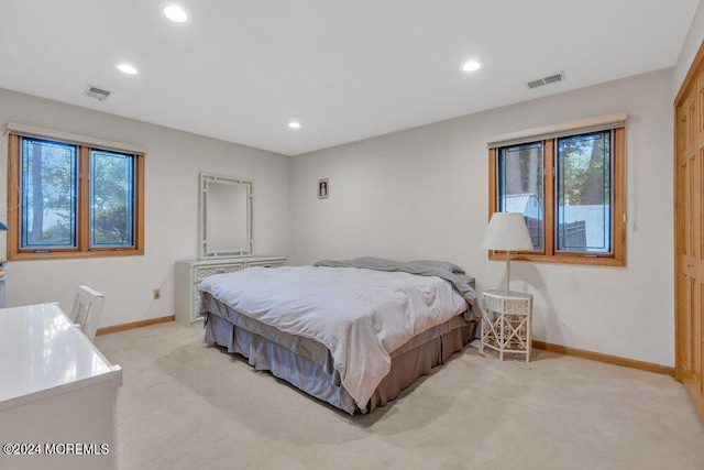 bedroom with light colored carpet, baseboards, visible vents, and multiple windows