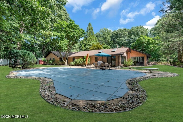 view of swimming pool featuring a yard, a patio, a diving board, and a covered pool