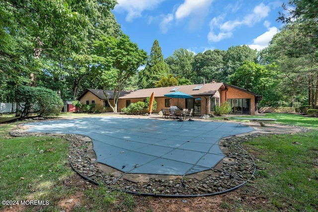 view of pool featuring a lawn, a diving board, a covered pool, and a patio area