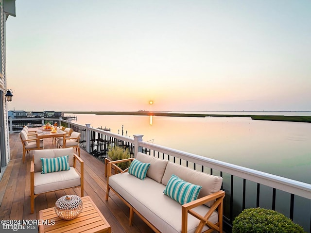 deck at dusk with an outdoor hangout area and a water view