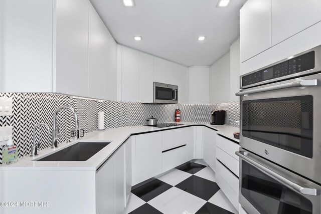 kitchen featuring sink, white cabinetry, backsplash, and stainless steel appliances