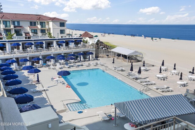 view of pool featuring a patio area, a beach view, and a water view