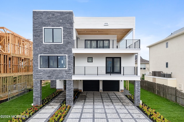 contemporary home featuring a balcony, a garage, and a front yard