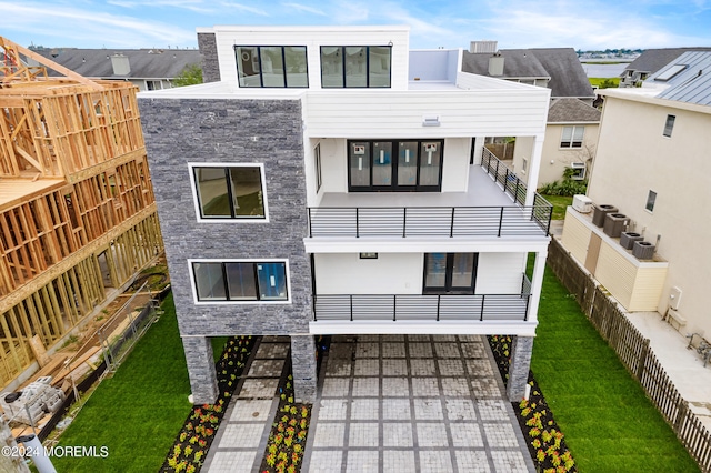 view of front of house featuring a balcony, central air condition unit, and a front yard