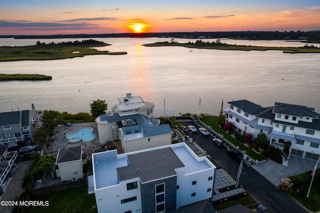 aerial view at dusk featuring a water view