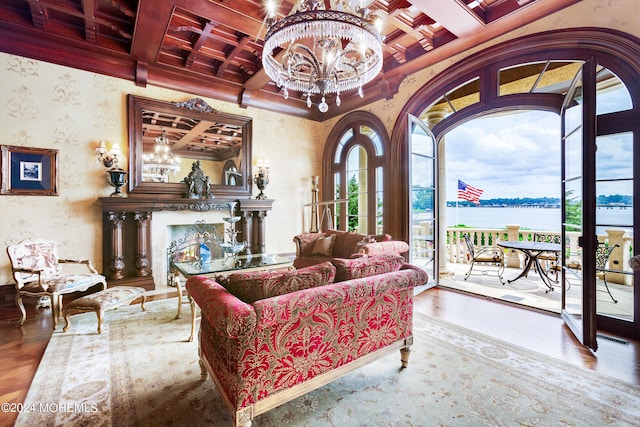 living room featuring coffered ceiling, a notable chandelier, wood-type flooring, and a water view