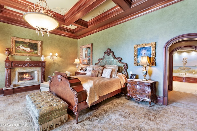 carpeted bedroom with ornamental molding, coffered ceiling, beamed ceiling, a high end fireplace, and ensuite bathroom