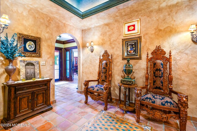 corridor with ornamental molding, a towering ceiling, and tile patterned floors