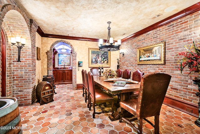 tiled dining area featuring crown molding, brick wall, a textured ceiling, and an inviting chandelier