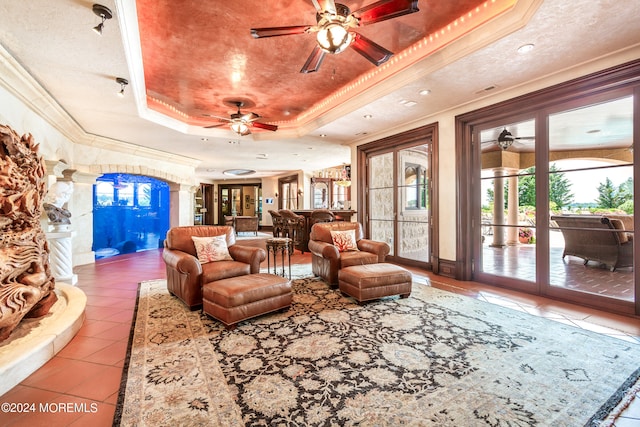 tiled living room with ceiling fan, crown molding, and a tray ceiling