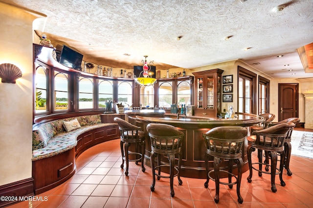 bar with a textured ceiling and light tile patterned floors