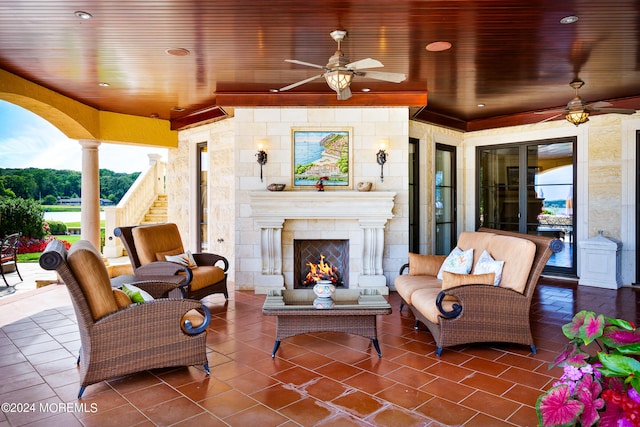 view of patio featuring ceiling fan and an outdoor living space with a fireplace