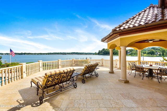 view of patio / terrace with ceiling fan, an outdoor living space, and a water view