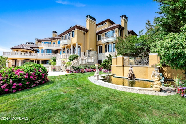 rear view of property with a balcony and a yard