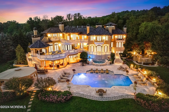 back house at dusk with a patio and pool water feature