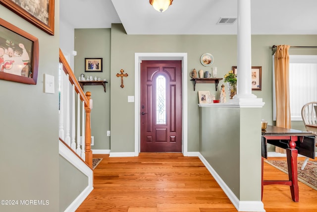 entryway with light wood-style flooring, visible vents, baseboards, stairway, and decorative columns