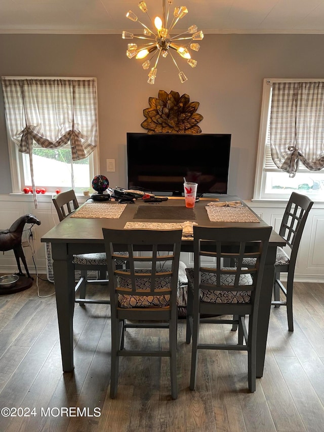 dining room with wood-type flooring, a notable chandelier, ornamental molding, and a healthy amount of sunlight