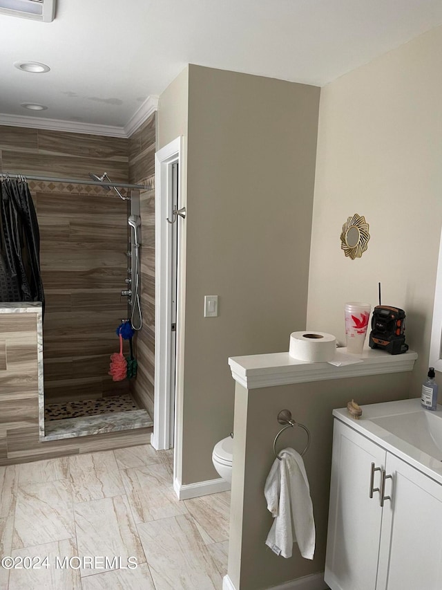 bathroom with ornamental molding, vanity, tile patterned floors, a tile shower, and toilet