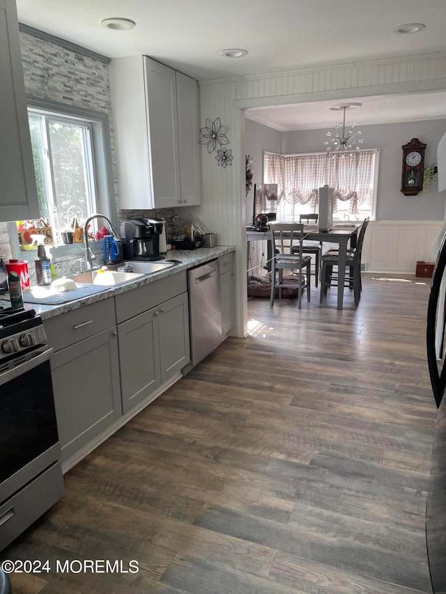 kitchen with dark wood-type flooring, gray cabinets, a chandelier, light stone countertops, and stainless steel appliances