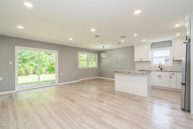 kitchen with a baseboard heating unit, stainless steel fridge, sink, and light hardwood / wood-style flooring