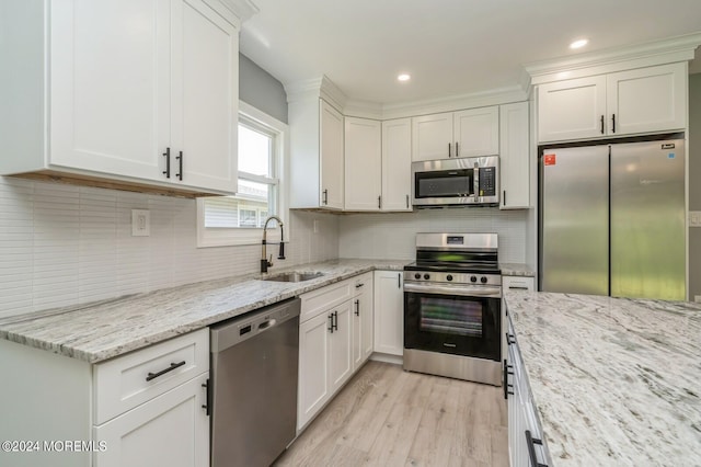 kitchen with decorative backsplash, appliances with stainless steel finishes, light stone counters, light hardwood / wood-style floors, and sink