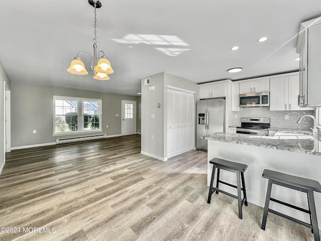 kitchen featuring sink, a baseboard radiator, appliances with stainless steel finishes, light hardwood / wood-style flooring, and light stone countertops