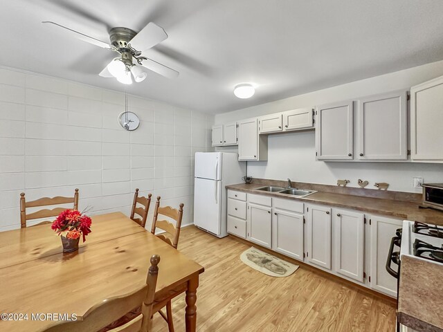 kitchen with sink, white appliances, white cabinetry, and light hardwood / wood-style flooring