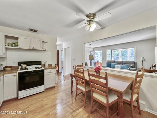 kitchen with white gas stove, light wood-type flooring, and white cabinetry