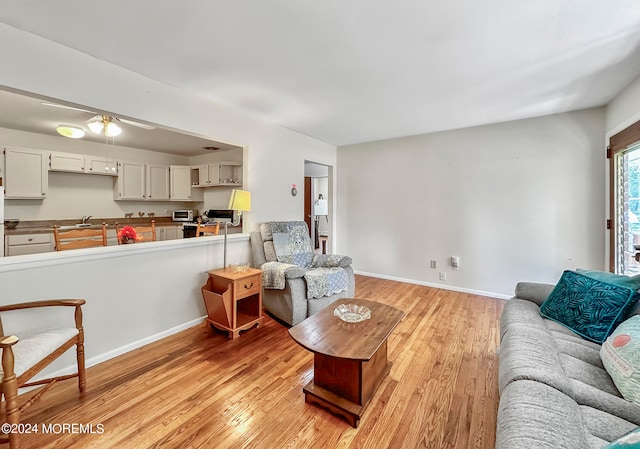 living room with ceiling fan, light wood-type flooring, and sink