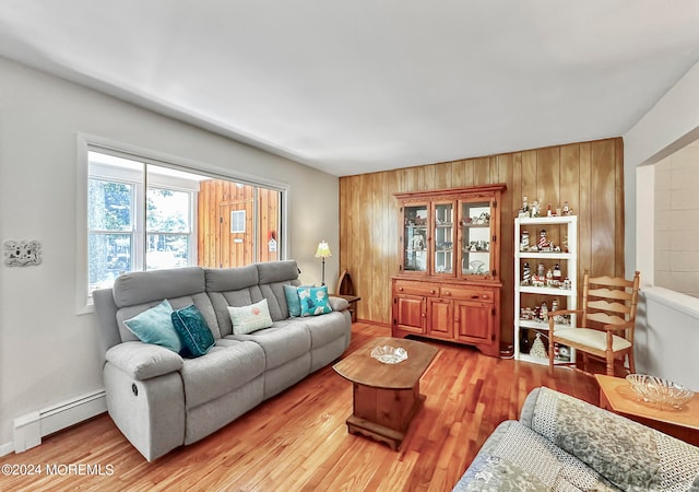 living room featuring light wood-type flooring, wooden walls, and baseboard heating