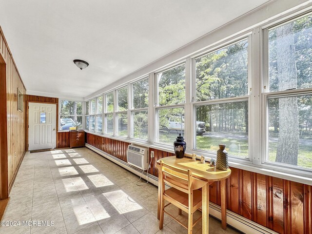 sunroom featuring a healthy amount of sunlight, a wall mounted AC, and baseboard heating