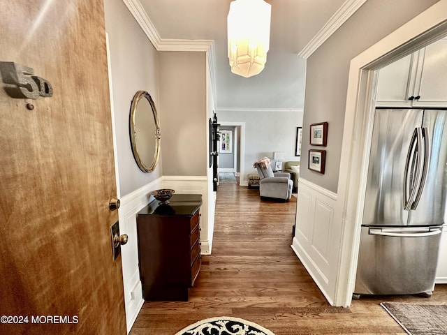 hall with an inviting chandelier, wood finished floors, crown molding, and wainscoting