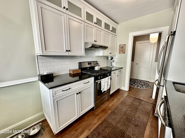 kitchen with stainless steel gas stove, dark countertops, glass insert cabinets, under cabinet range hood, and white cabinetry