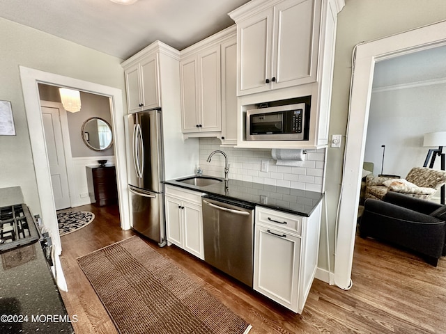 kitchen with dark wood-style flooring, stainless steel appliances, tasteful backsplash, white cabinets, and a sink