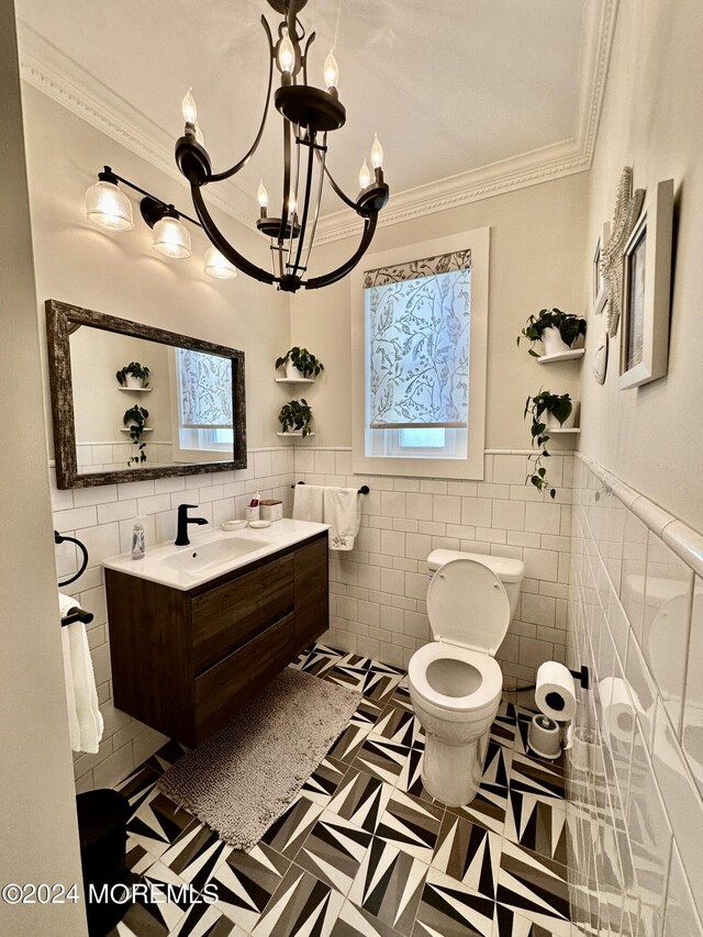 bathroom with wainscoting, toilet, crown molding, vanity, and tile walls