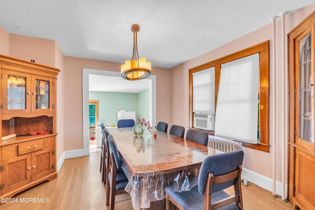 dining room featuring an inviting chandelier, light hardwood / wood-style floors, cooling unit, and radiator