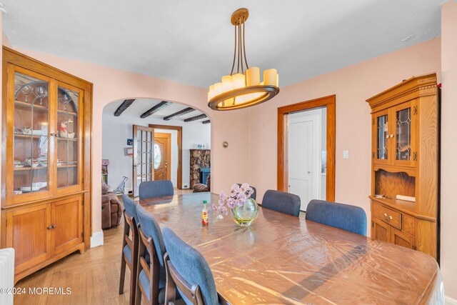 dining space with beamed ceiling, light parquet floors, and a fireplace