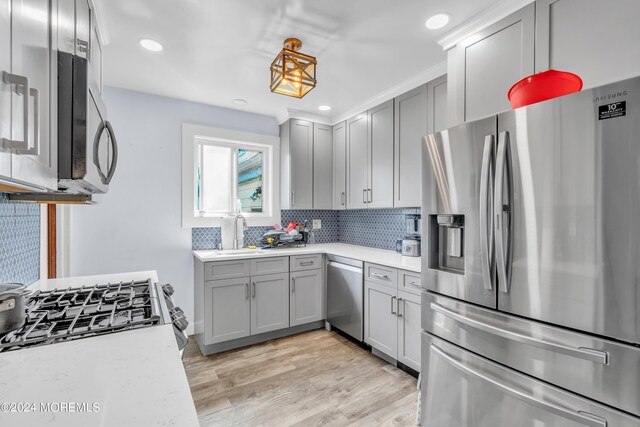 kitchen featuring light hardwood / wood-style floors, stainless steel appliances, decorative backsplash, and gray cabinetry