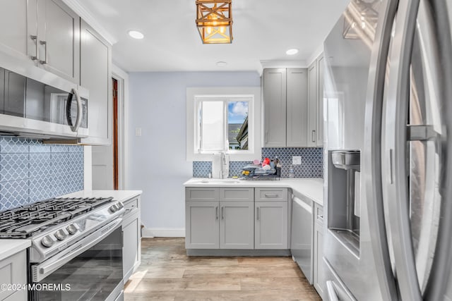 kitchen featuring decorative backsplash, light wood-type flooring, gray cabinets, appliances with stainless steel finishes, and sink