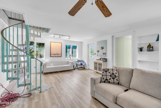 living room featuring ceiling fan, light hardwood / wood-style floors, track lighting, and built in features